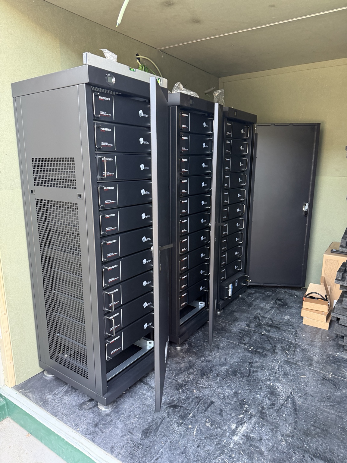 Trois armoires ouvertes de batteries haute tension — 150 kWh de stockage